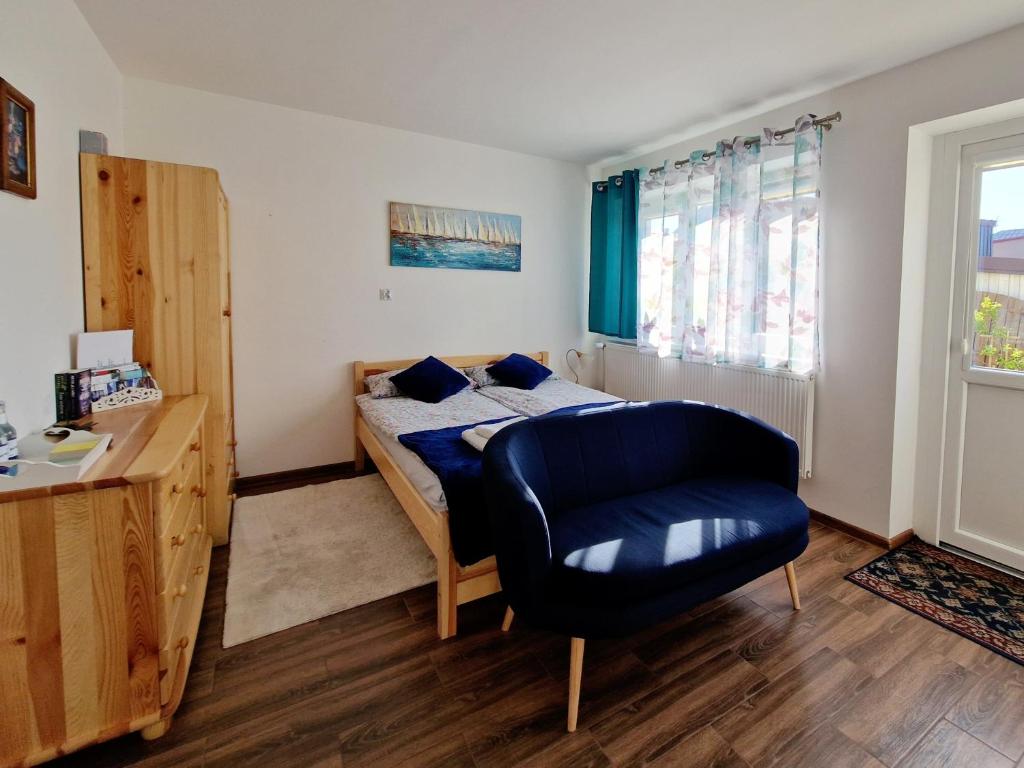 a bedroom with a bed and a blue chair at Apartament Cicho Sza in Augustów