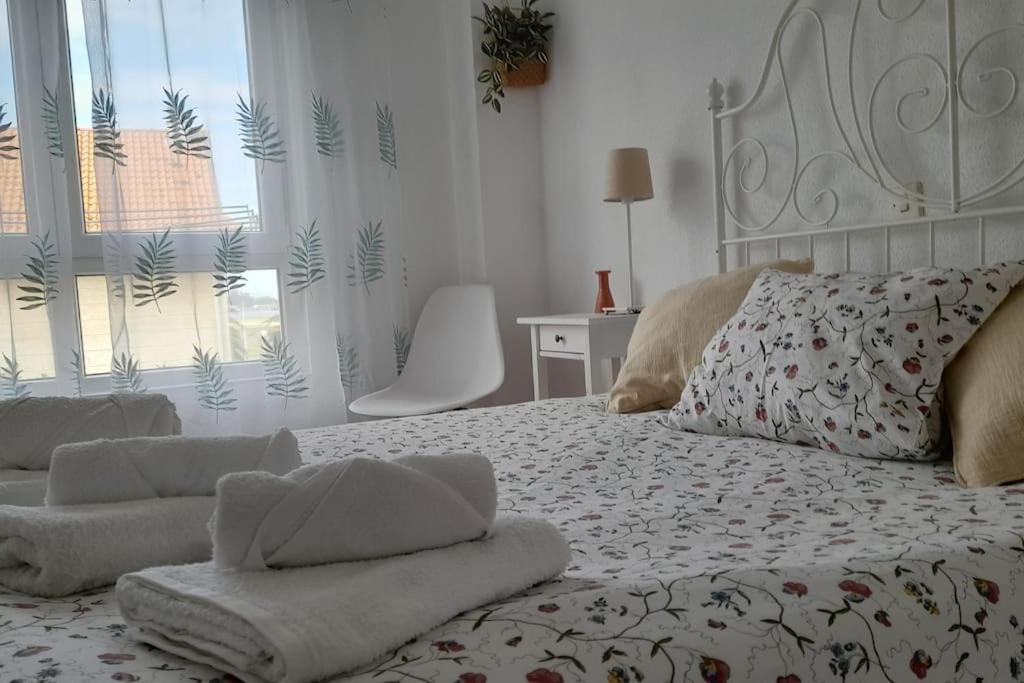 una camera da letto bianca con un letto e asciugamani di Coqueto apartamento a dos minutos de la playa a Somo