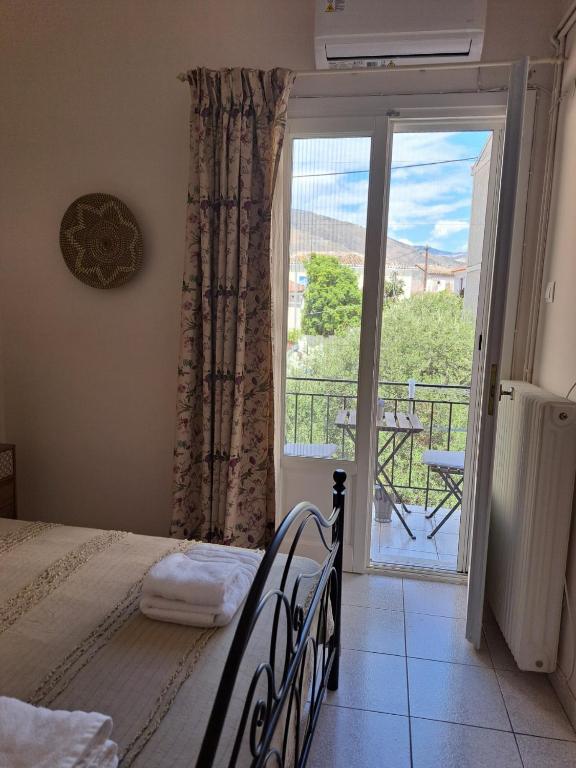 a bedroom with a bed and a balcony with a view at Penny's Beach Cottage in Galaxidi