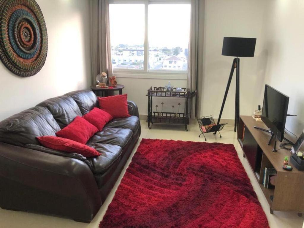 a living room with a leather couch and a red rug at Buenos Aires 705 in Osório