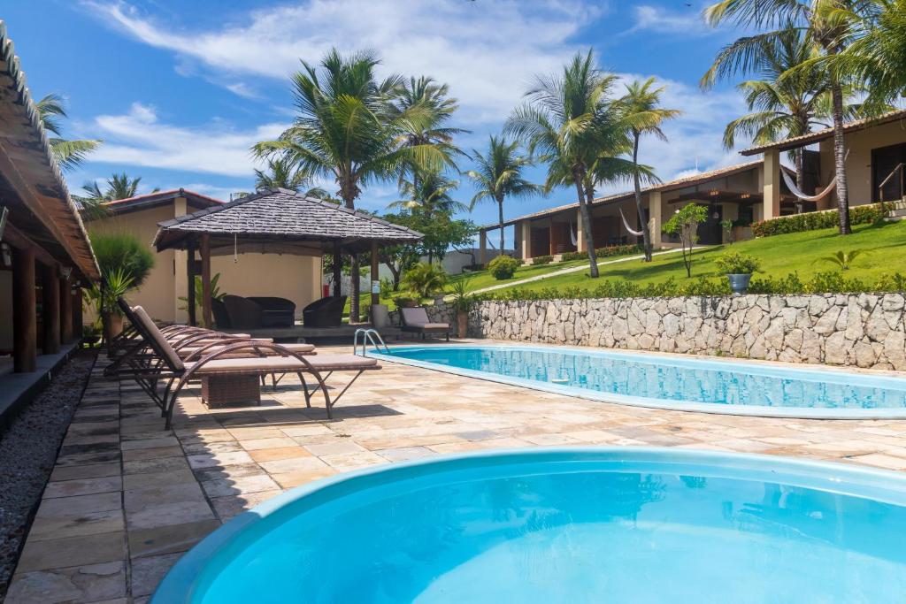 a swimming pool with a patio and a house at Hotel Villaggio Tudo Bom in Uruau