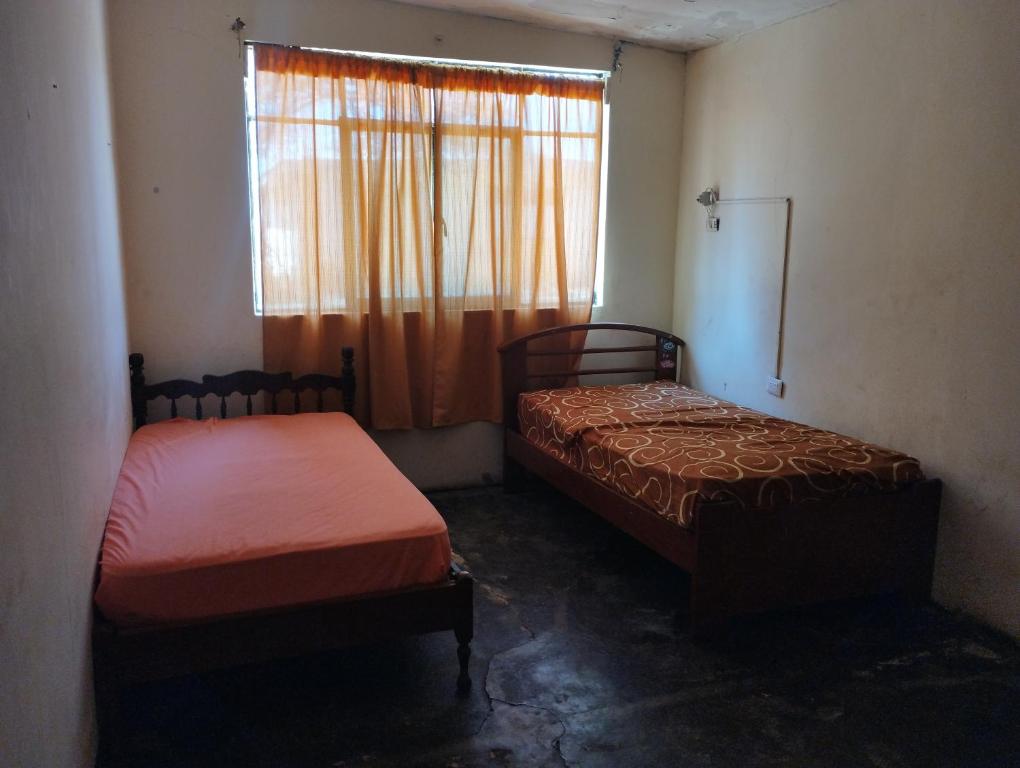 two beds in a small room with a window at Hospedaje Cora in Piura