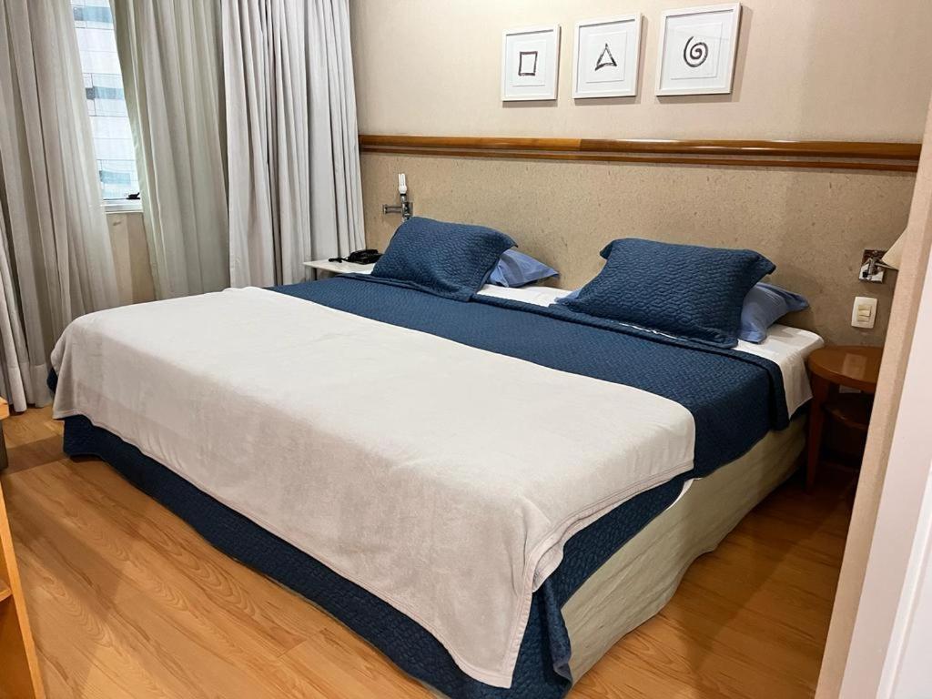 a bedroom with a large bed with blue pillows at Flat Vila Olímpia ao lado do Shopping in Sao Paulo