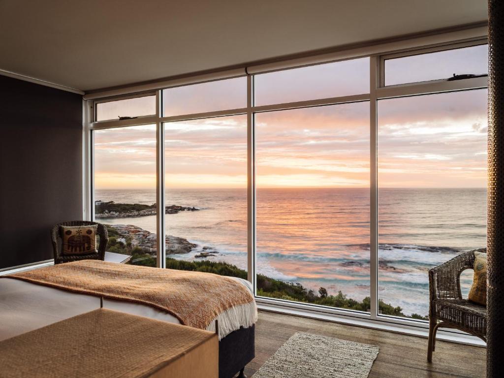 a bedroom with a large window view of the ocean at Holland House Bay of Fires in Binalong Bay