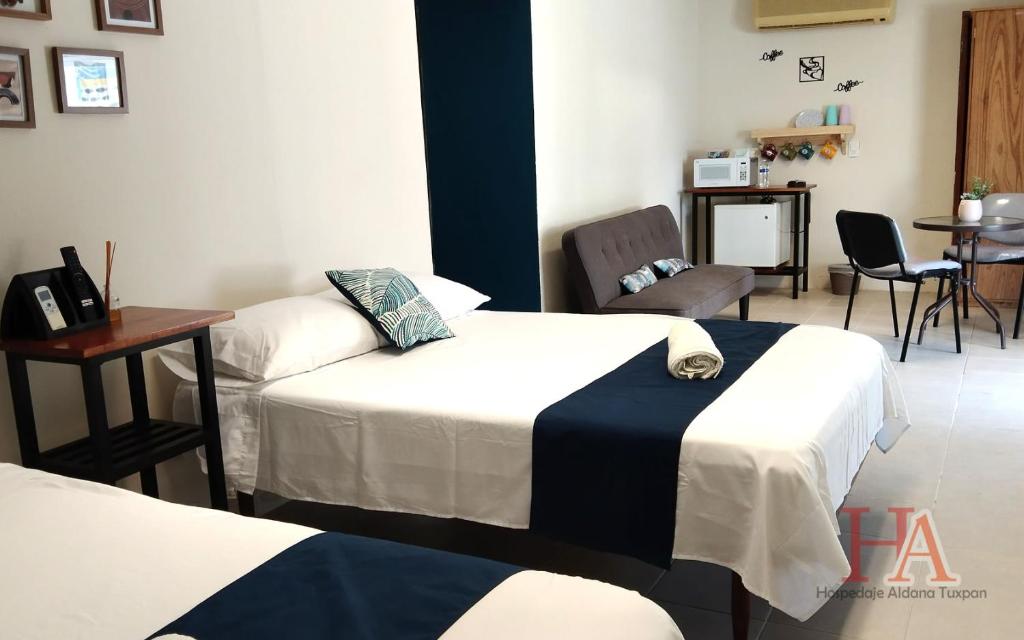 um quarto com duas camas e uma mesa e cadeiras em Hospedaje Aldana - Habitación L E R D O en zona centro em Tuxpan de Rodríguez Cano