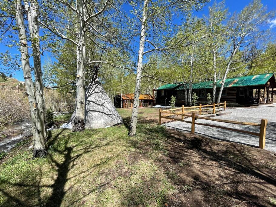 una cabaña en el bosque con una valla y árboles en Sleepy Hollow in Ferncliff - Hot Tub, en Allenspark