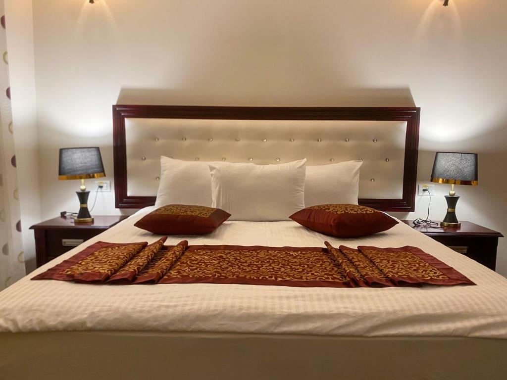 a bedroom with a bed with two pillows and two lamps at Abu Mazen Hotel in Khirbat an Naşārá