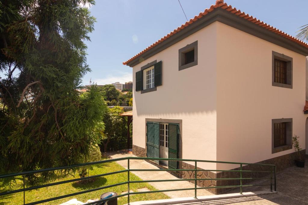a white house with a green door and stairs at Pilar House in Funchal