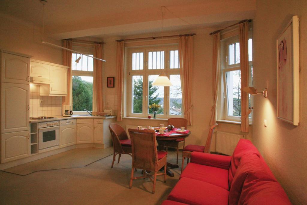 ein Wohnzimmer mit einem roten Sofa und einem Tisch in der Unterkunft Villa Daheim - FeWo 04 in Ostseebad Kölpinsee