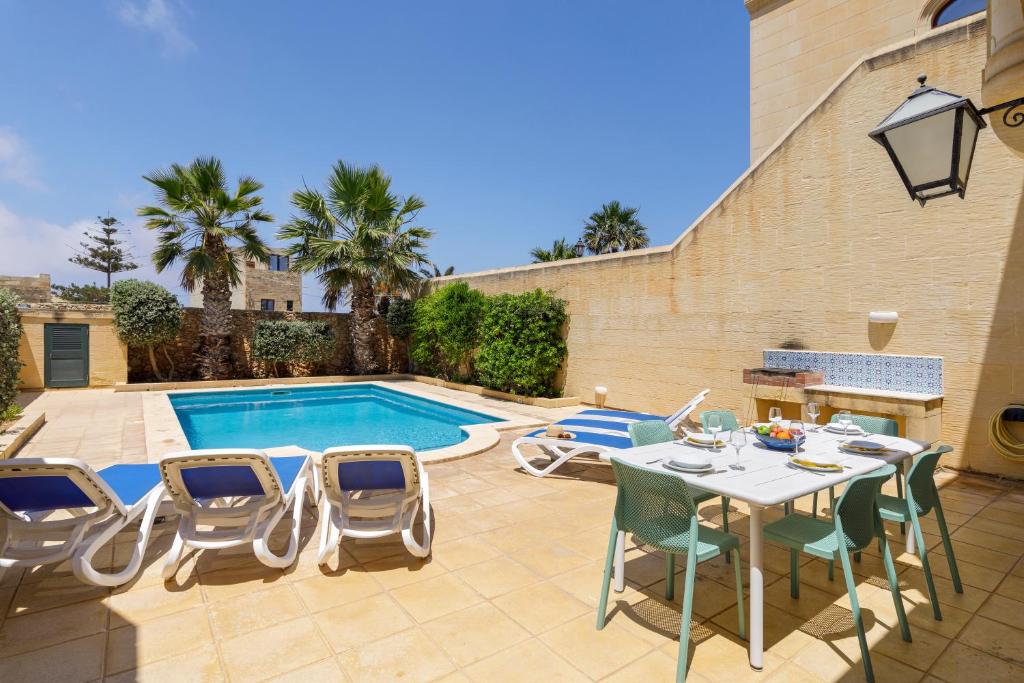 d'une terrasse avec une table et des chaises à côté de la piscine. dans l'établissement Gozo Escape, à Għasri