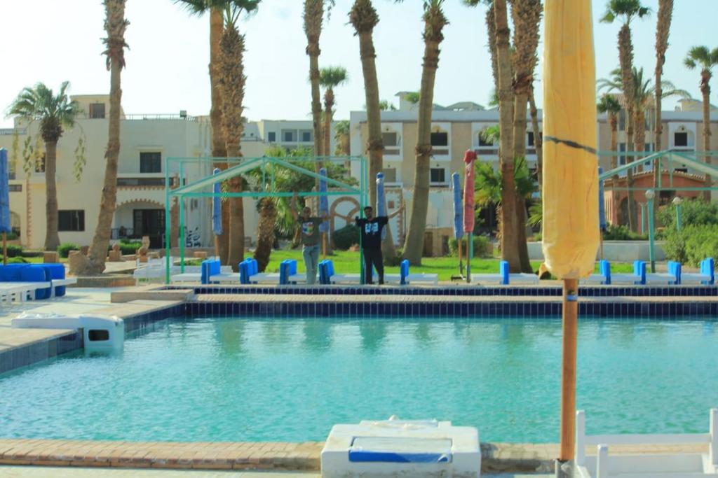 ein Pool mit Palmen und eine Person im Hintergrund in der Unterkunft Mashrabiya Hotel in Hurghada