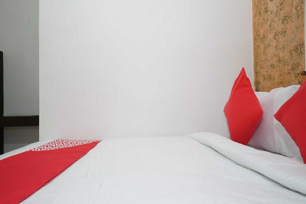 a bed with red and white pillows on it at OYO Flagship 81100 Hotel Sai Lodging in Māngvādi