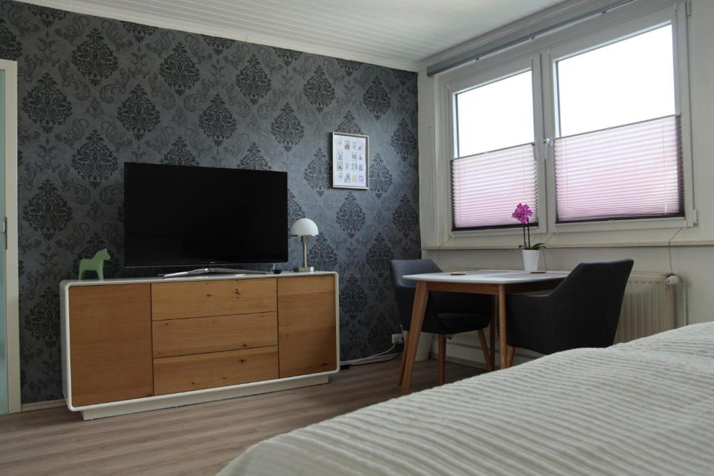 1 dormitorio con TV en un tocador y escritorio en Privatzimmer mit eigenem Bad und Küche, en Burgwedel