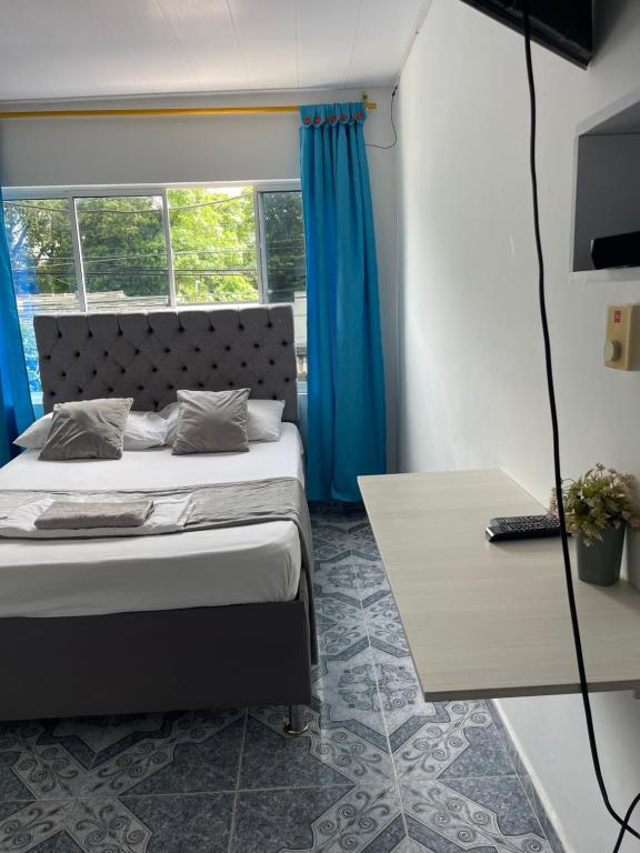 1 dormitorio con 1 cama con cortinas azules y mesa en HospedajeLR, en Barrancabermeja