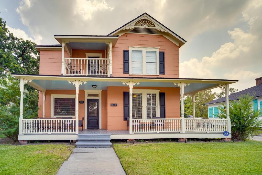 a pink house with a large front porch at Lake Charles Vacation Rental - Walk to the Lake! in Lake Charles