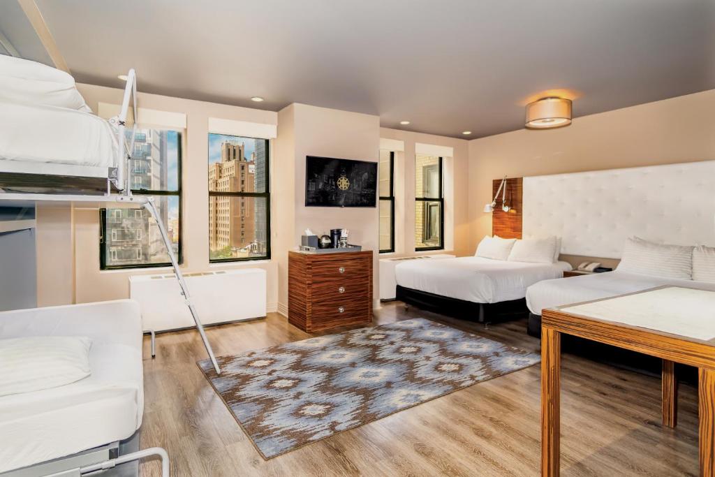 a bedroom with two beds and a desk in it at The Gallivant Times Square in New York