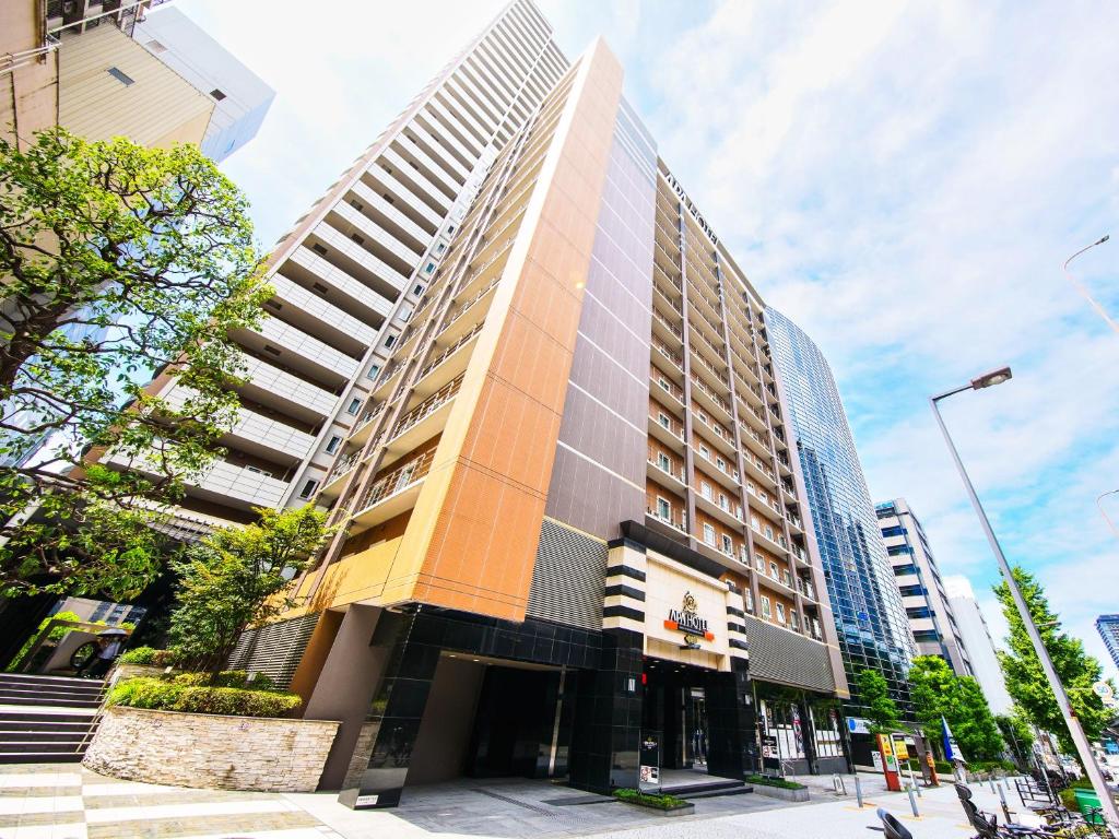 APA Hotel Osaka Tanimachi Yonchome-Ekimae في أوساكا: مبنى طويل على شارع المدينة وبه مباني طويلة