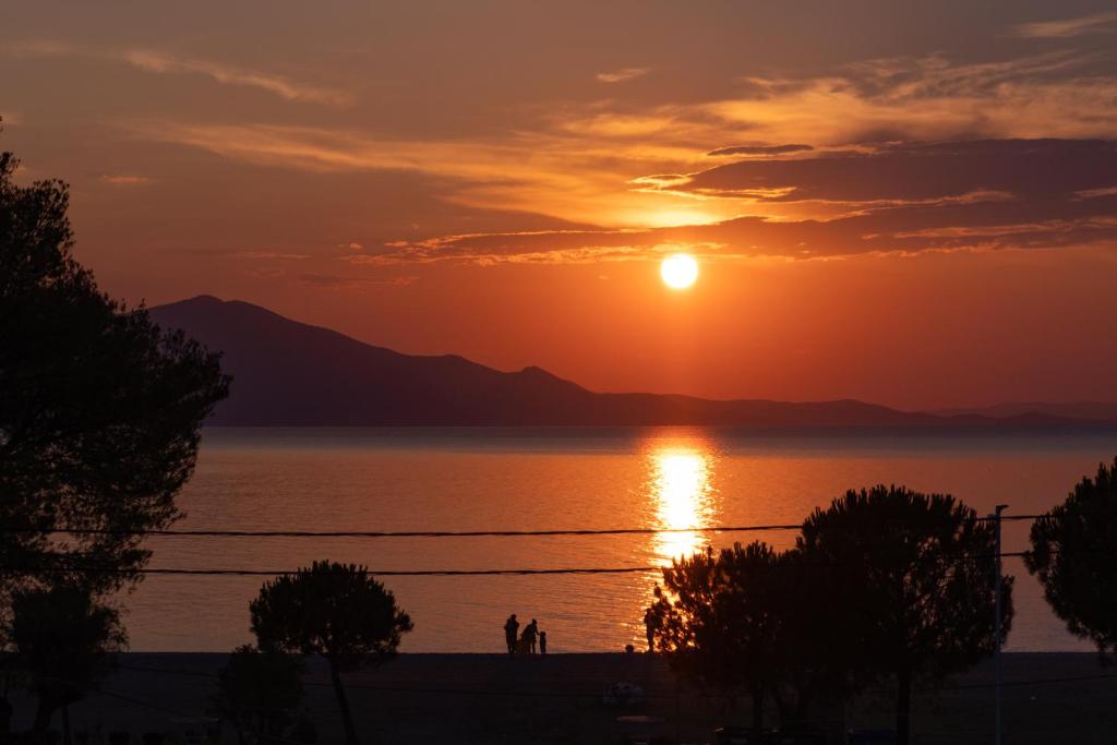 a sunset over a body of water with people standing in front at DIMITRA APARTMENTS in Pefki