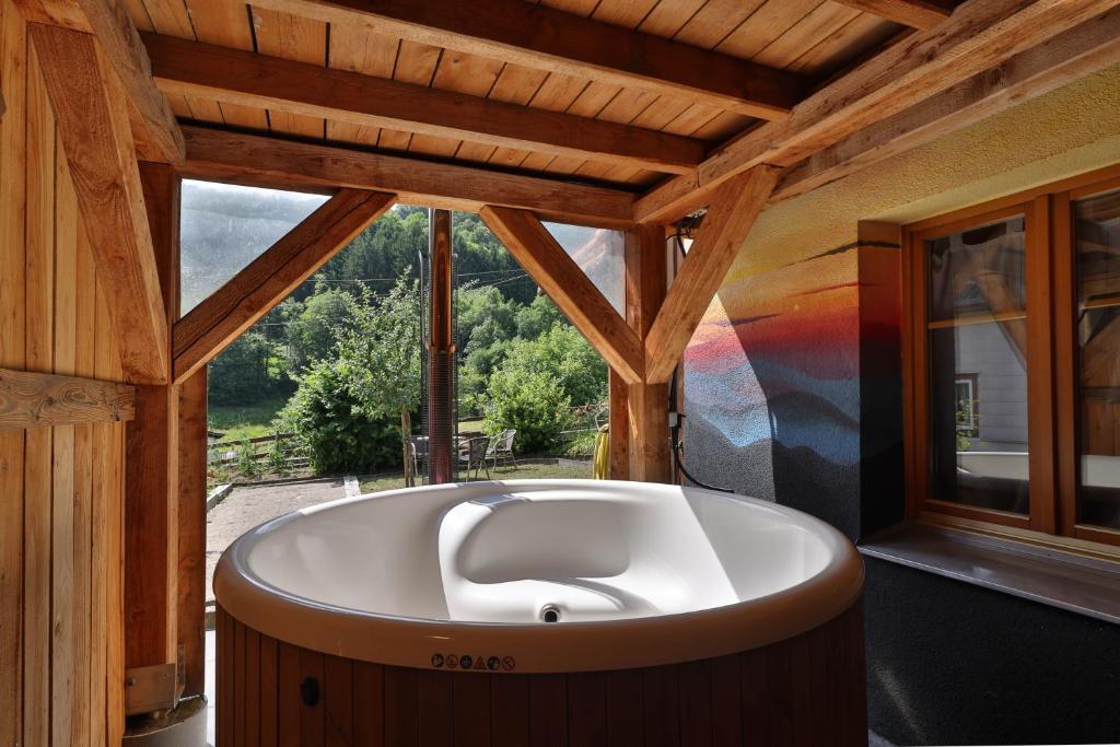 uma grande banheira num quarto com uma janela em Le Chalet du Tanet spa sauna terrasse en Alsace em Soultzeren