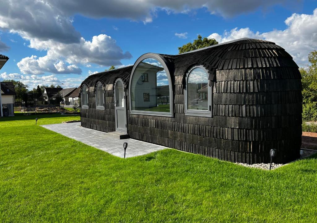 a black building in a field of green grass at Tirolian Lodge North, Whirlpool, Sauna, Lagerfeuer in Bundorf