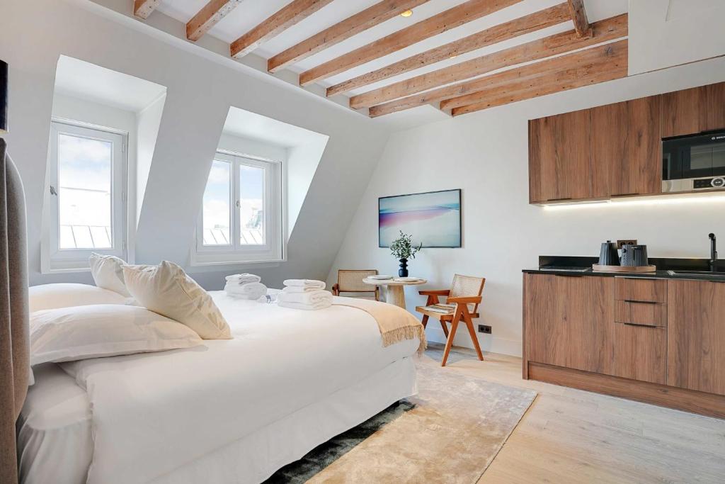 - une chambre blanche avec un grand lit et une cuisine dans l'établissement Stylish Studio - 2P - Vendôme Square, à Paris