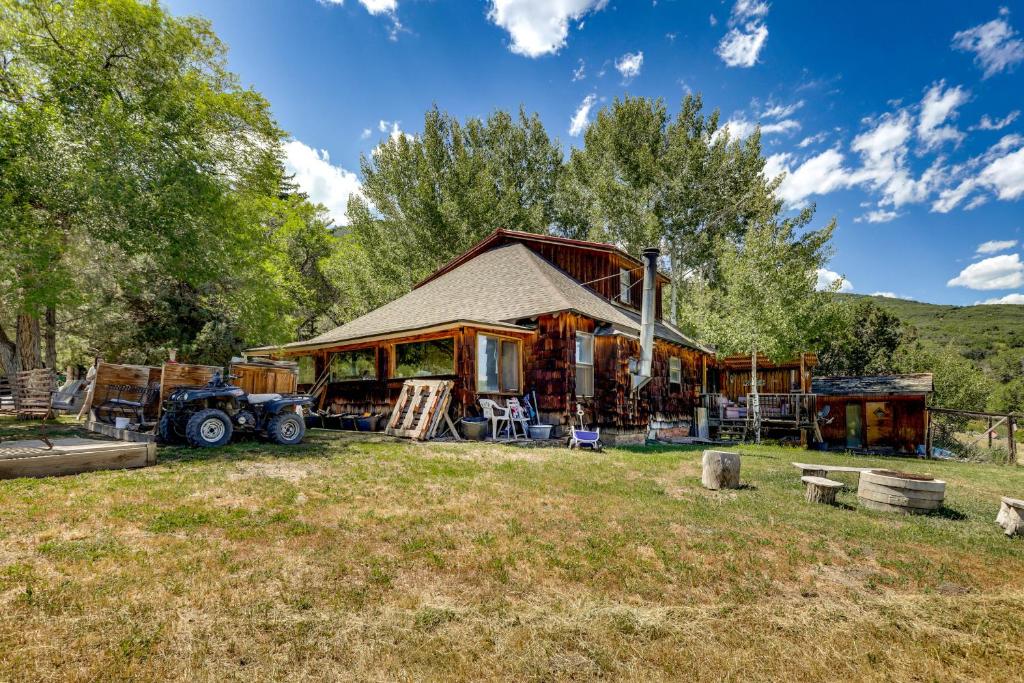 a log cabin with a tractor parked in front of it at Historic Alpine Cabin with Scenic Mount Sopris View in Glenwood Springs