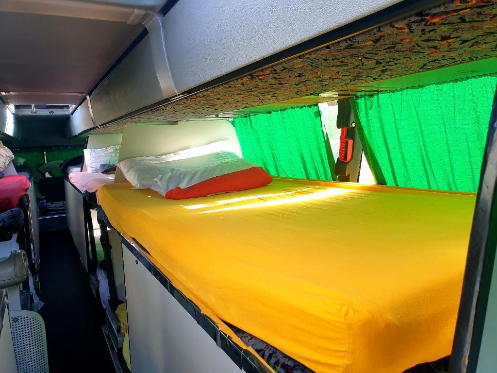 een bed in een camper met groene en gele gordijnen bij Kapsuły Sypialne AutokarSingliPL, Par, ciekawe miejsce in Władysławowo