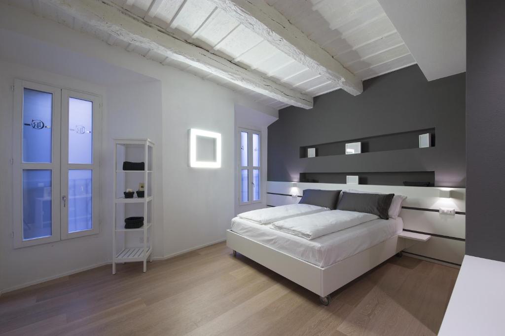 a white bedroom with a white bed and some windows at Como Luxury Rooms in Como