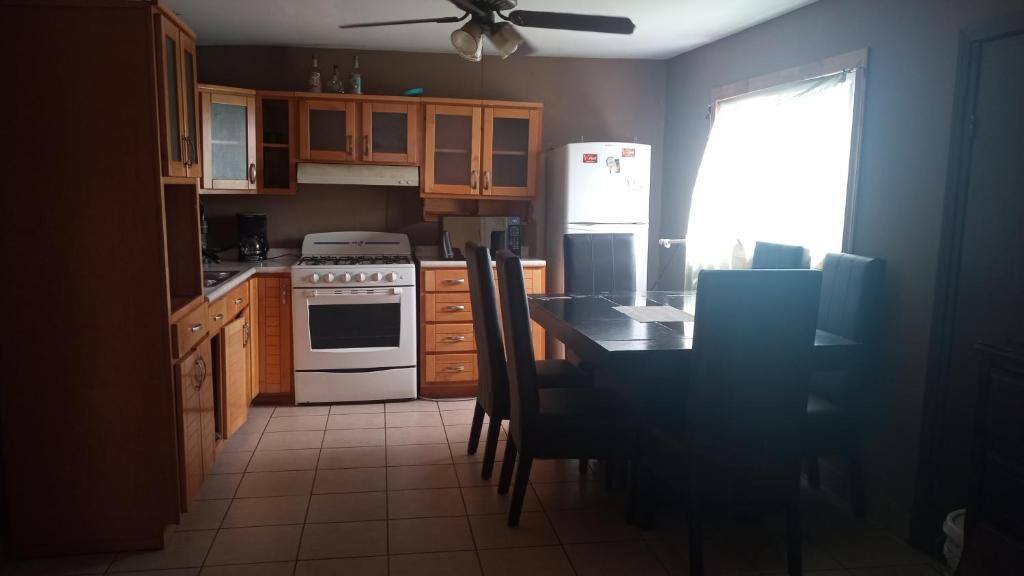 uma cozinha com uma mesa e um frigorífico branco em Casa shoke em Rosarito