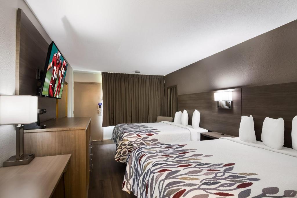 ein Hotelzimmer mit 2 Betten und einem Flachbild-TV in der Unterkunft Red Roof Inn Vero Beach - I-95 in Vero Beach