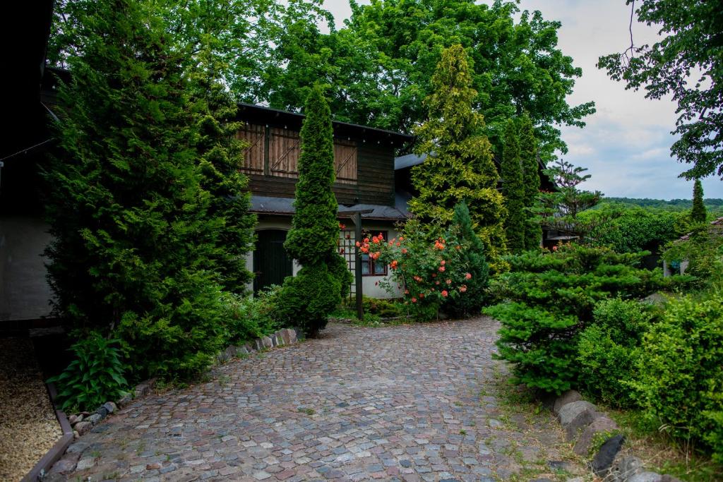 une maison avec des arbres et une allée en briques dans l'établissement Młynarzowy Dworek, à Gdynia