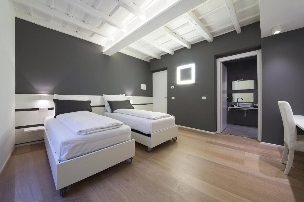 a bedroom with two beds and a white ceiling at Como Luxury Rooms in Como