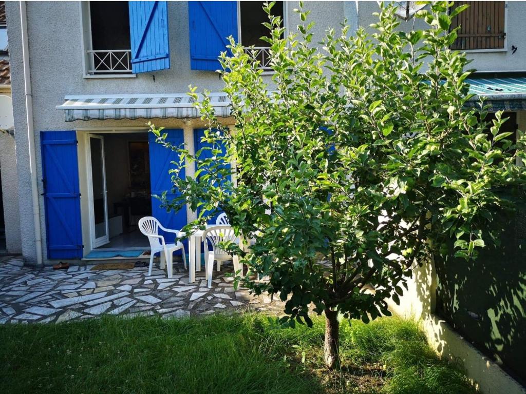 une maison avec des portes bleues et des chaises et un arbre dans l'établissement La maison bleue, à Épluches