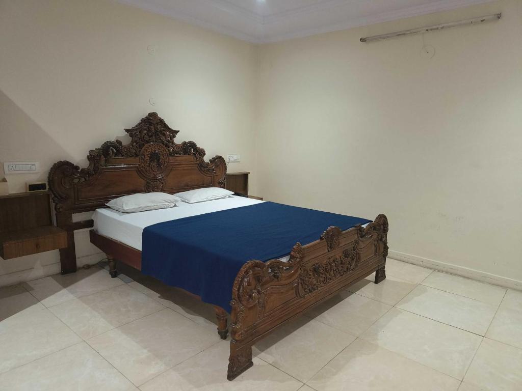 a bedroom with a large wooden bed with blue sheets at Collection O 81233 Mr Residency in Hyderabad