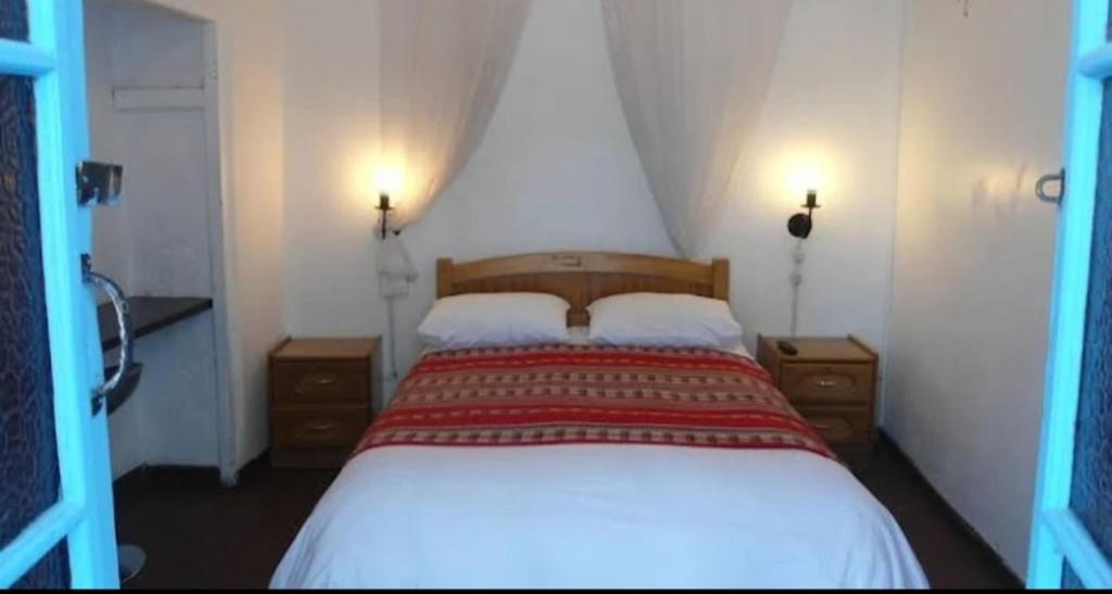 een slaapkamer met een groot wit bed en 2 nachtkastjes bij Albergue Galusa in Arequipa