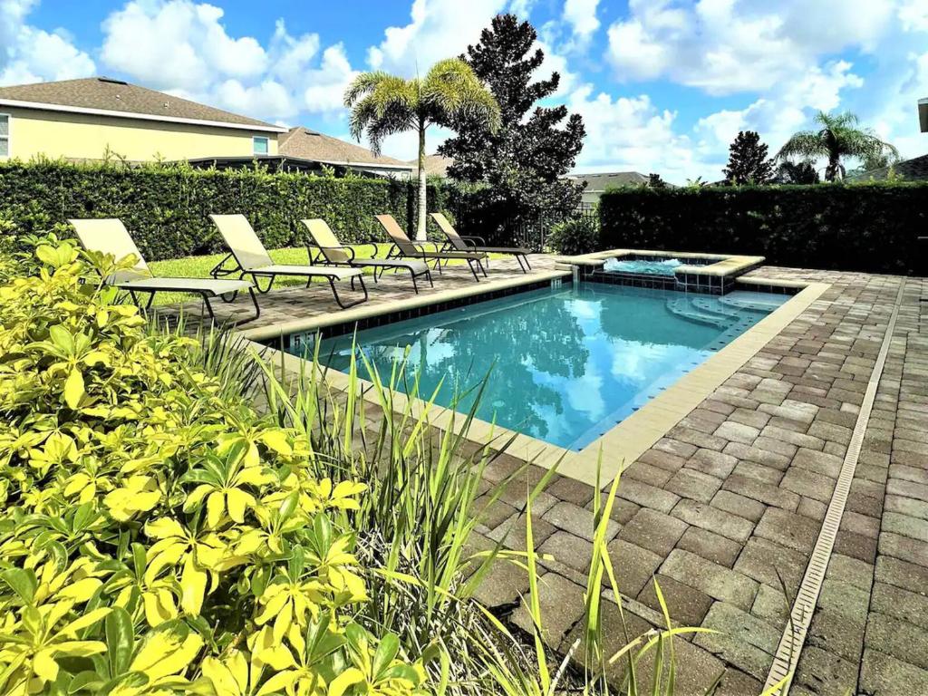 a swimming pool with lounge chairs next to a house at Deluxe Stay w Pool Spa Game Room BBQ Grill in Orlando