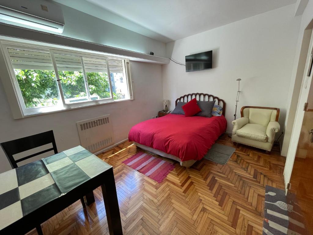 1 dormitorio con 1 cama roja y 1 silla en Castex y Salguero en Palermo Chico 10min Aeroparque 100m Mater Dei en Buenos Aires