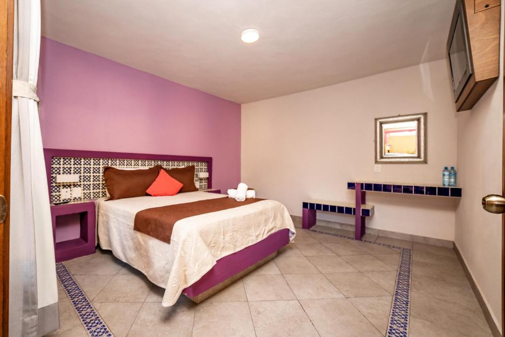 - une chambre avec un lit et un mur violet dans l'établissement El Jazmin de Zanya, à Dolores Hidalgo