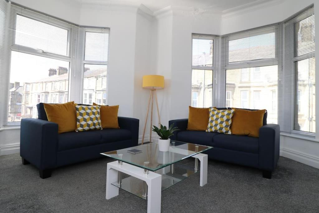 a living room with two blue couches and a coffee table at Modern 3 Double Bedroom Town Centre Maisonette in Morecambe