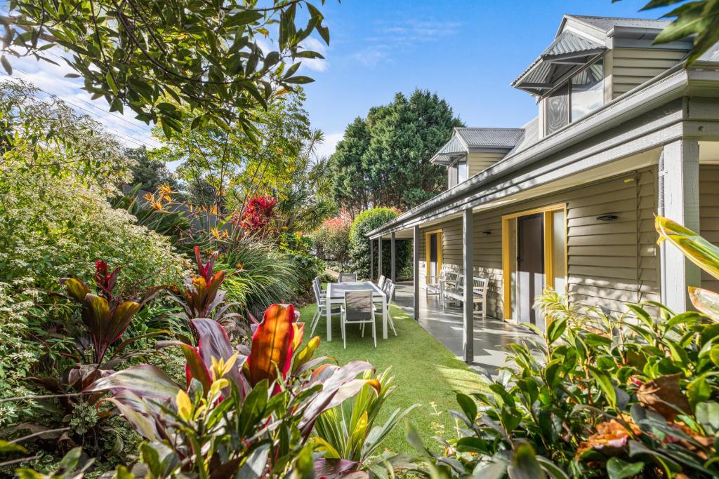 um jardim com uma mesa e cadeiras ao lado de uma casa em Jandar Retreat Maleny em Maleny