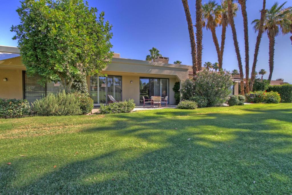a house with palm trees in front of a yard at VY236 - Sunny Palm in Palm Desert