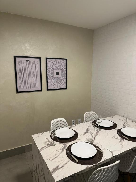 una mesa con platos y sillas blancos en una habitación en Sudoeste, sua busca termina aqui, Lindo apt na Clsw 103, en Brasilia