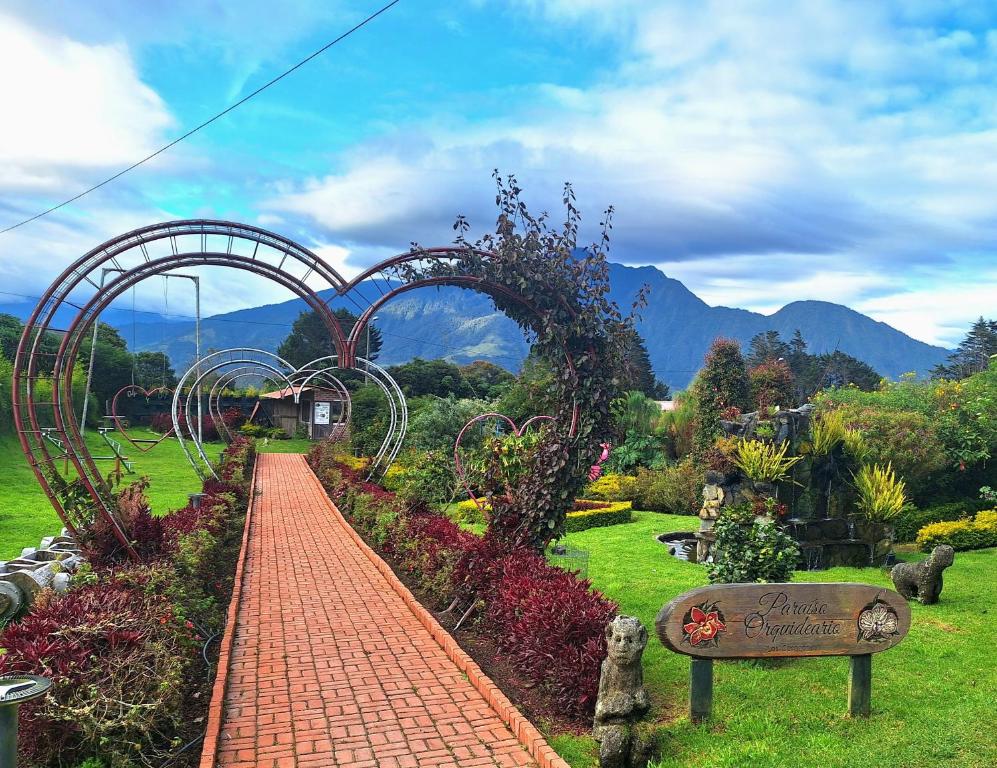 un jardín con un arco y una pasarela de ladrillo en Paraiso Orquideario, en Baños