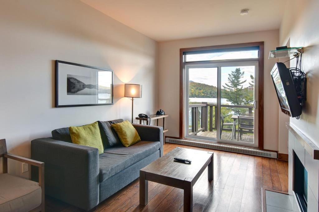 Deluxe Suite - View on Lake & 6 Min from Tremblant Versant Nord في لاك سوبريور: غرفة معيشة مع أريكة ومدفأة