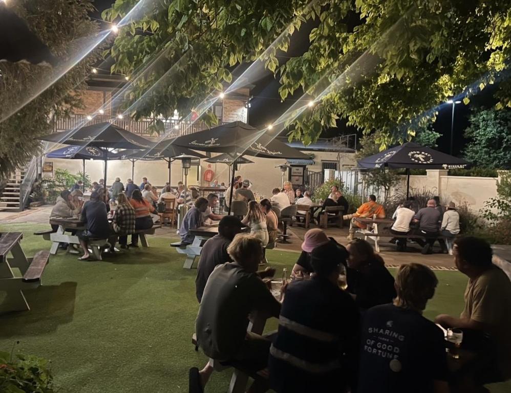 un grupo de personas sentadas en un parque por la noche en Belmore Hotel Scone, en Scone