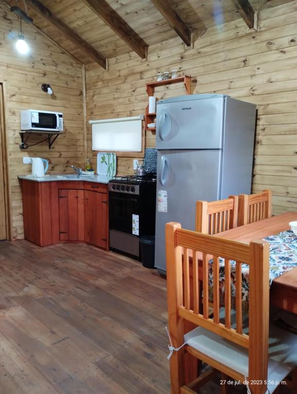 una cocina con nevera y mesa en Cabañas Los Patricios, en Colón