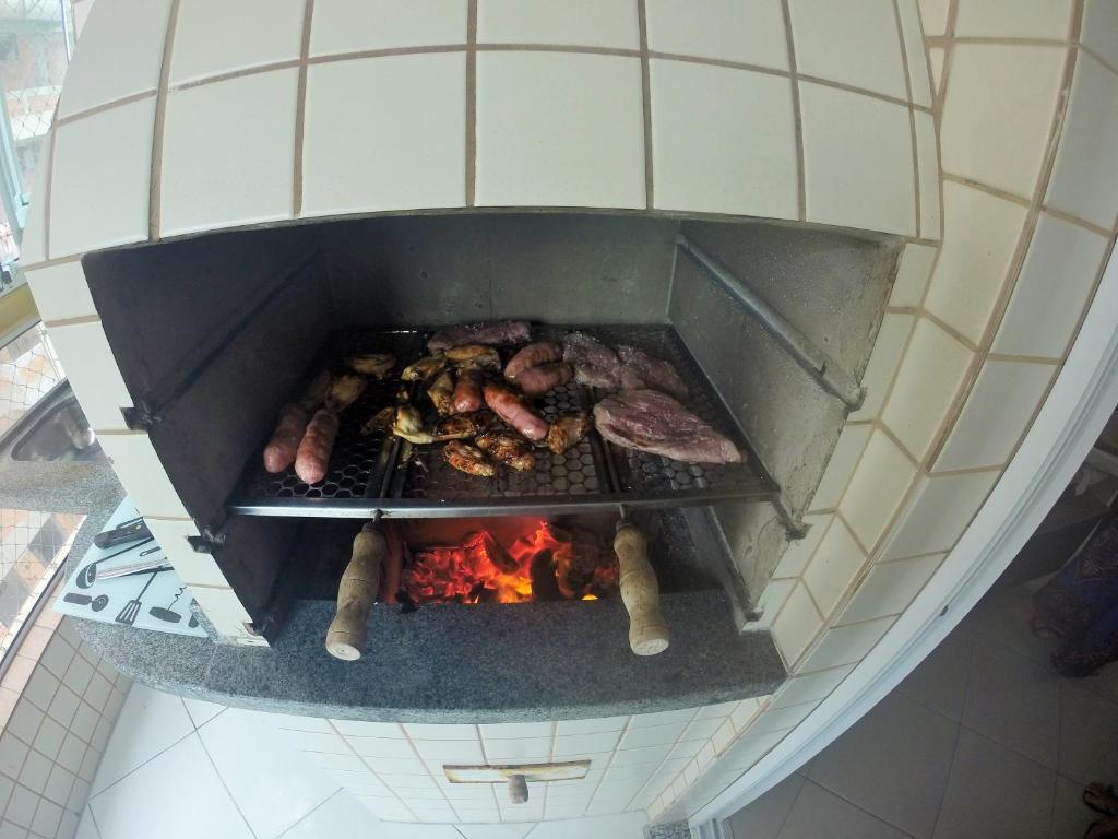 une vue aérienne d'un gril avec de la viande et du feu dans l'établissement Cantinho do Churrasco - Varanda Gourmet a 60 mts praia, à Praia Grande