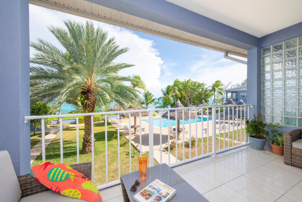 a balcony with a view of a pool and palm trees at Beach Living at Moon Bay with SeaView in Bodden Town