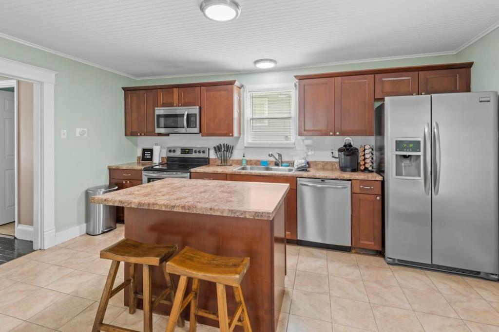 a kitchen with wooden cabinets and a stainless steel refrigerator at 4 Bedroom House, sleeps 12, short walk to Main St! in St. Charles