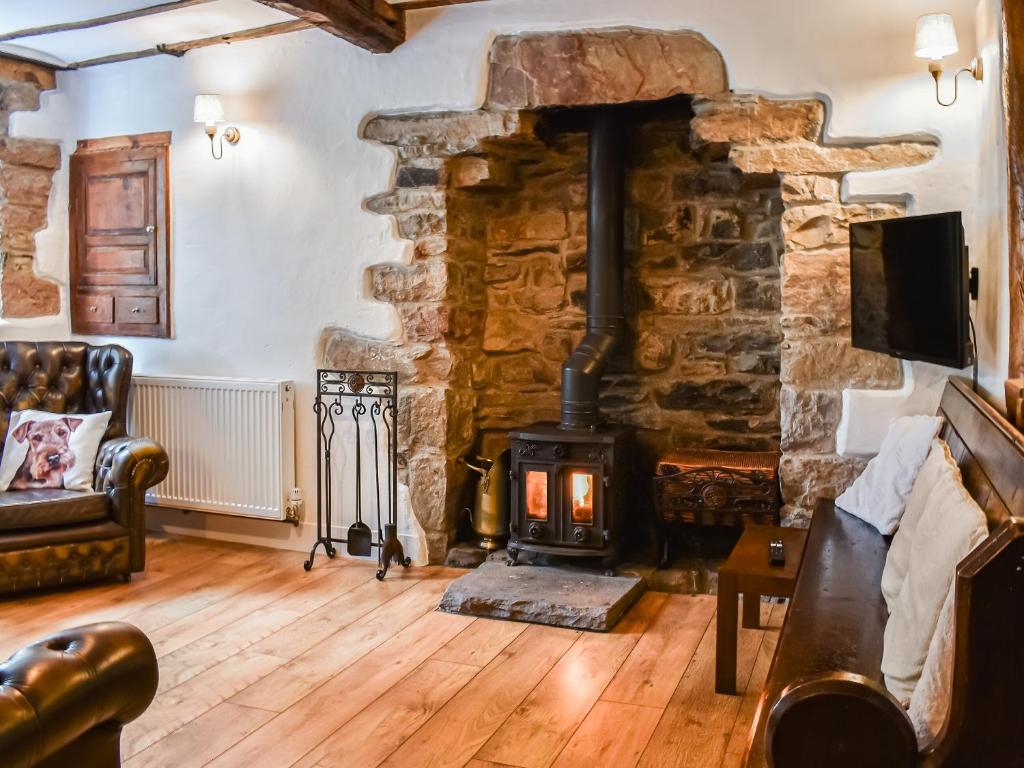 a fireplace in a living room with a stone wall at Greystones in Ravenstonedale
